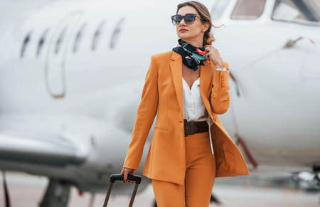 Connecteur agence de voyage - Femme sortant d'un avion, en tailleur orange