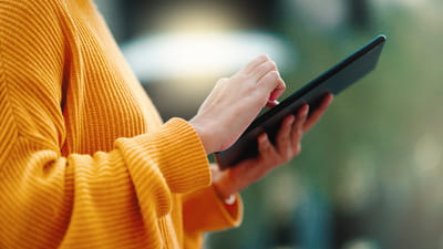 Ggros plan des mains d'une femme sur une tablette, pull orange