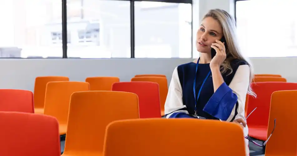Femme caucasienne au téléphone, assise dans une salle de conférence vide