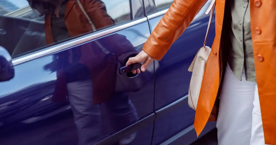 Close up of a caucasian woman opening her car door, wearing an orange jacket