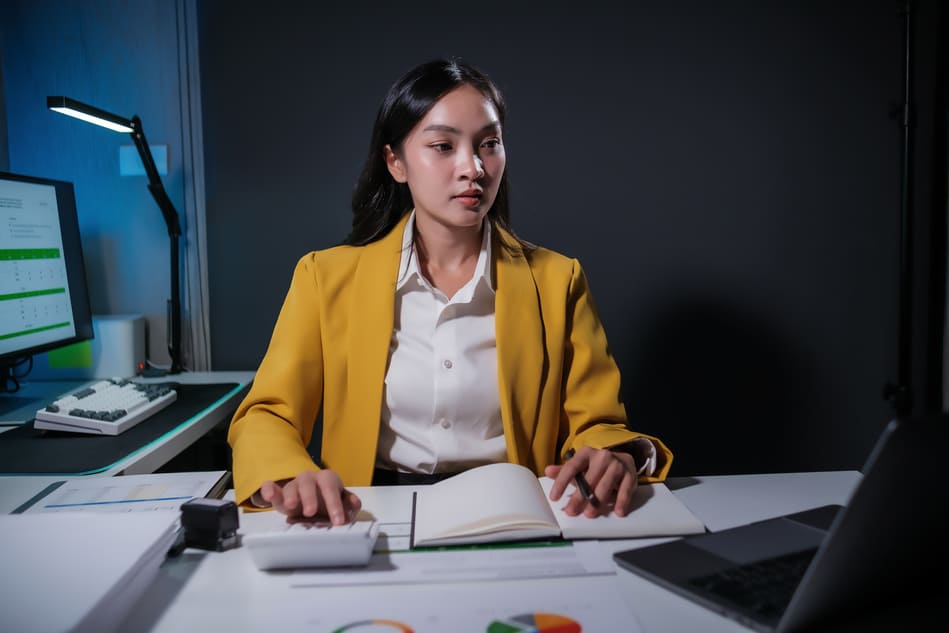 Collaboratrice portant une veste jaune, assise à son bureau