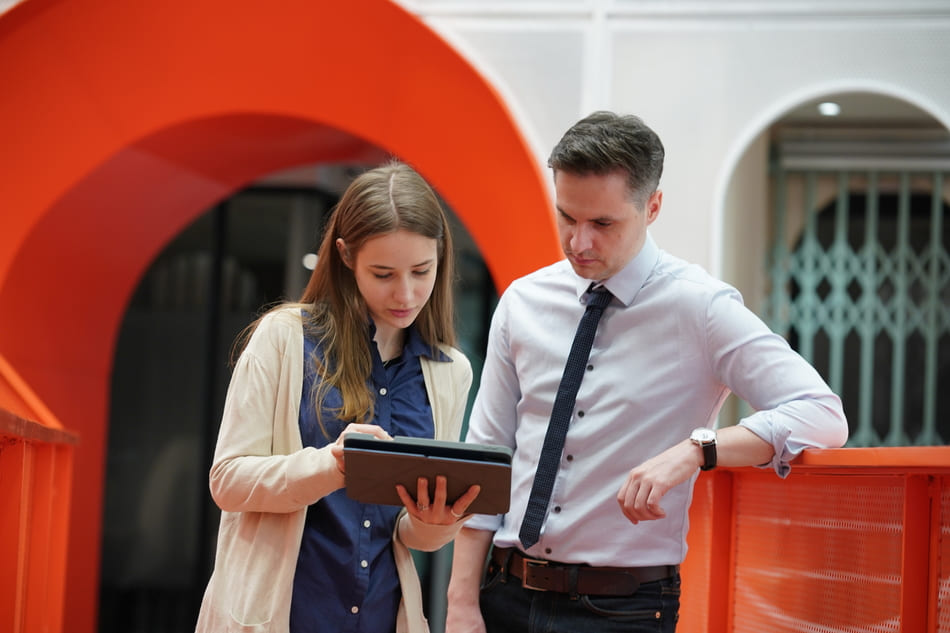 Female manager showing something to a young male intern on a tablet