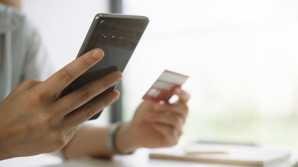 Close up of a woman's hands, holding a banking card and a phone