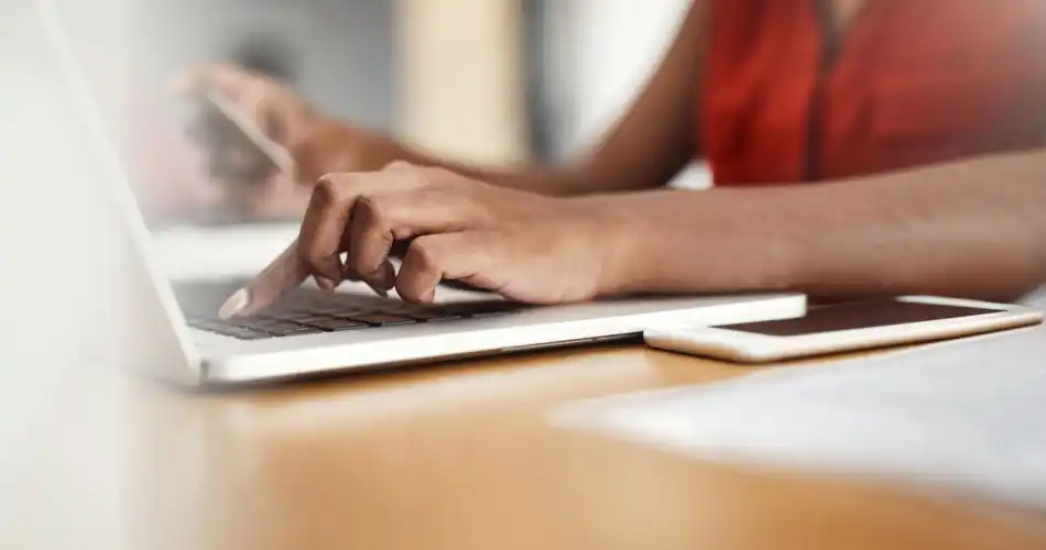 Gros plan sur les mains d'une personne tapant sur le clavier de son laptop