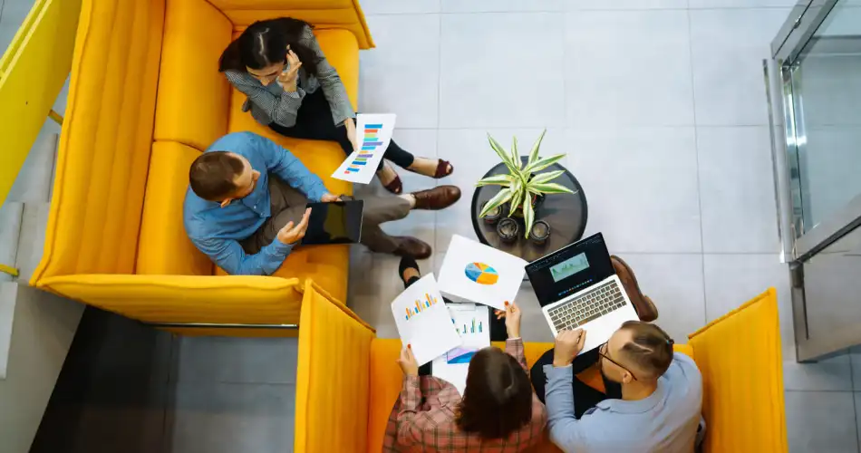 Group of coworkers seeing from above, working around a coffee table