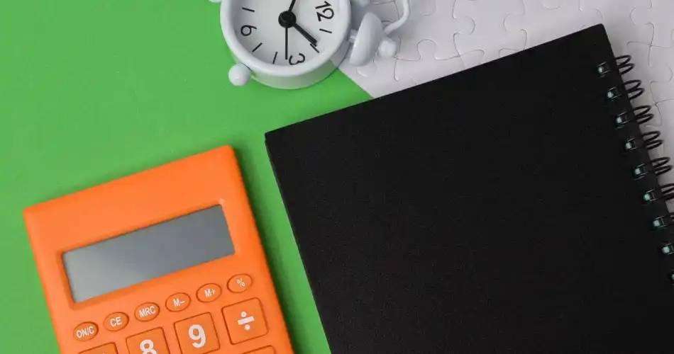 Gros plan d'une calculatrice orange et d'un cahier noir sur un bureau