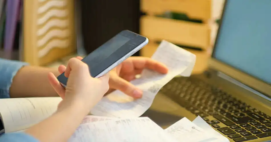 Gros plan sur les mains d'une personne prenant son ticket de caisse en photo