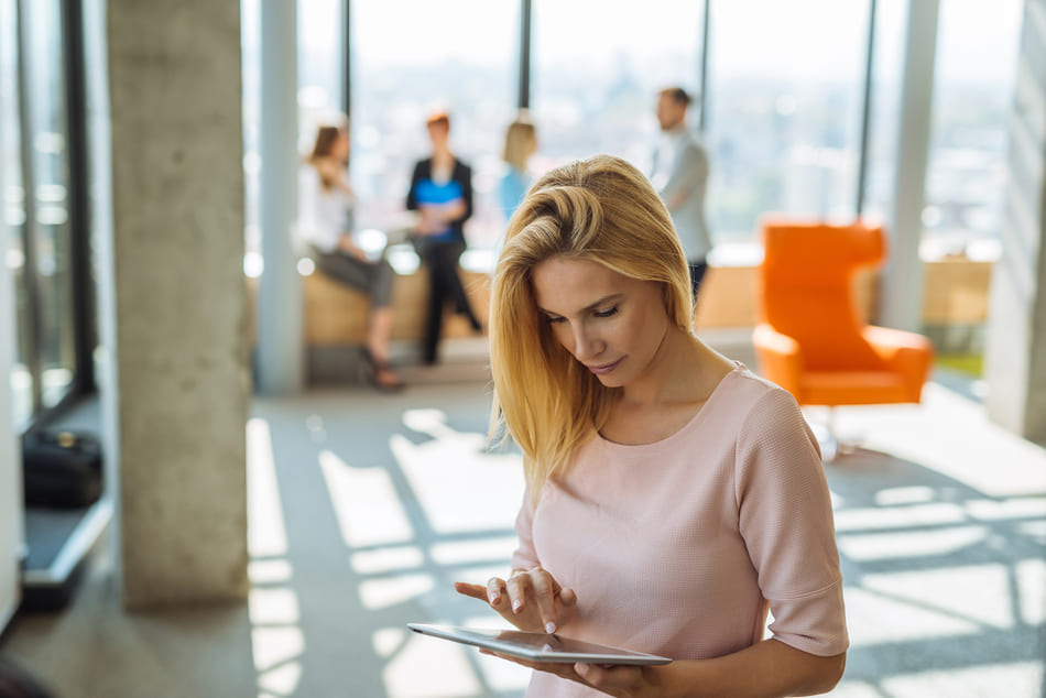 Woman using tablet with coworkers in the background