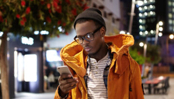 Young man on a business trip, with his phone in his hand and an orange jacket