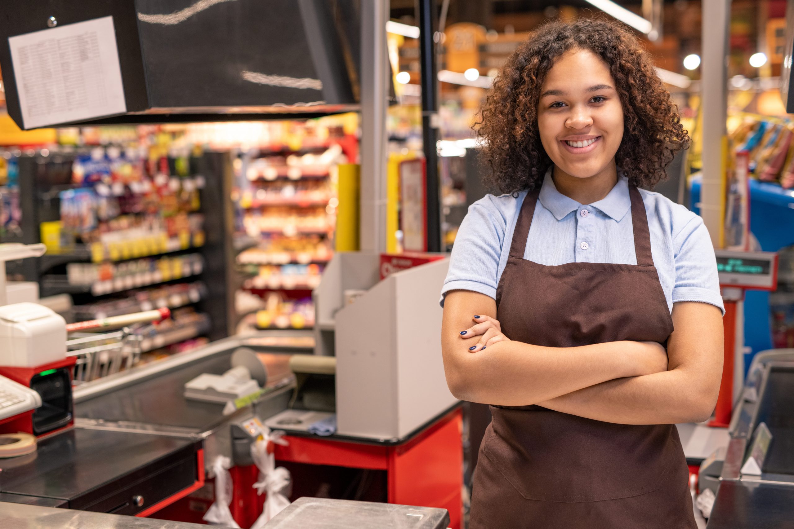 Jeune femme souriant devant une caisse