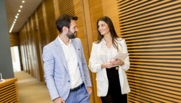 Une collaboratrice et un collaborateur discutent dans un couloir