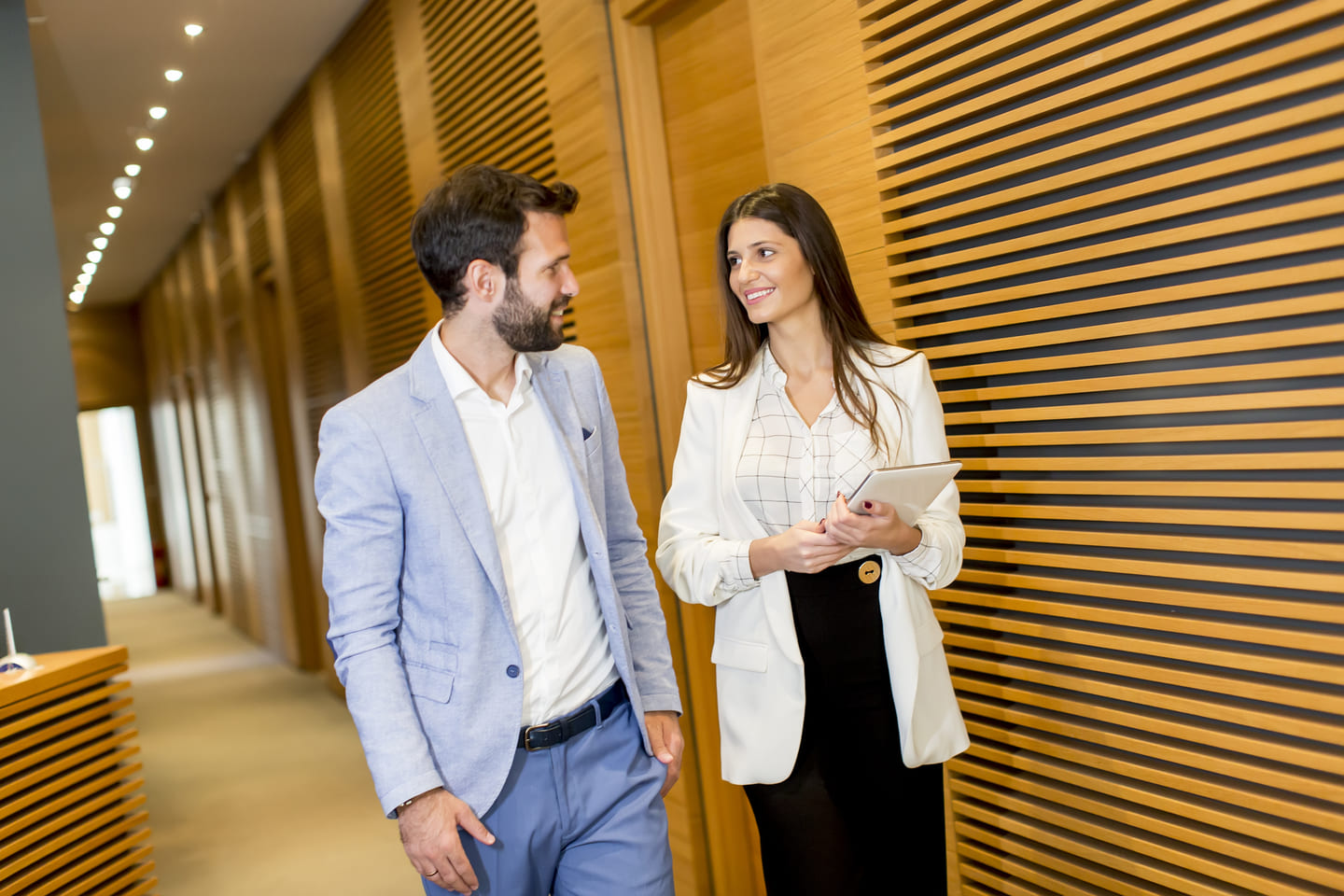 Une collaboratrice et un collaborateur discutent dans un couloir